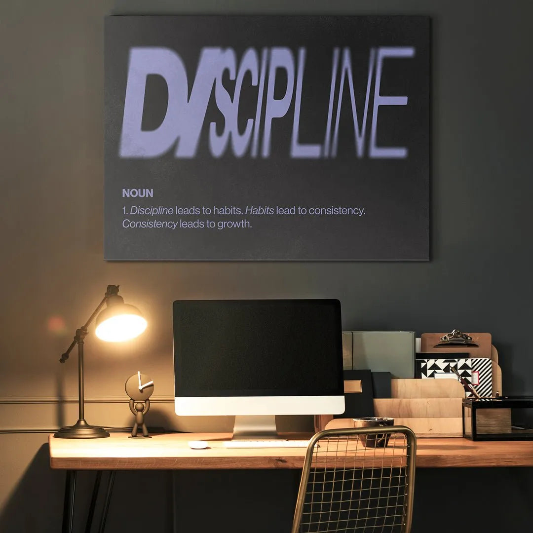 Lifestyle shot of the 'Discipline Definition' poster hanging above a clean office desk