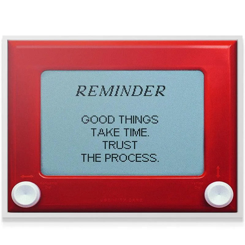 Low-angle shot emphasizing the bright red plastic frame holding the inspirational 'Good Things Take Time' message.