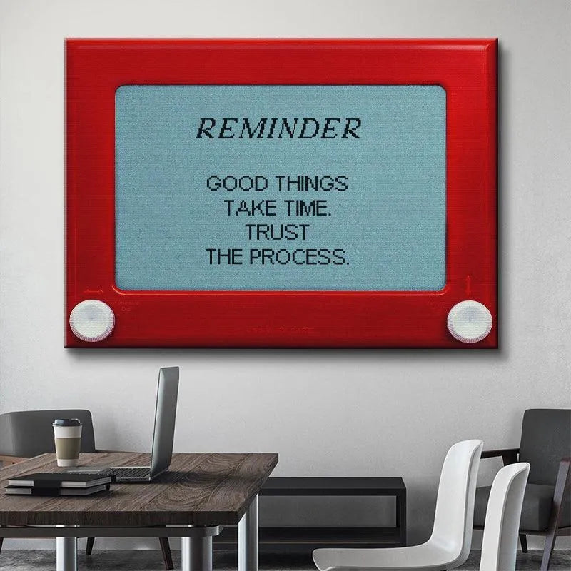 Lifestyle photo showing the 'Good Things Take Time' art piece on a wooden office desk next to a laptop.