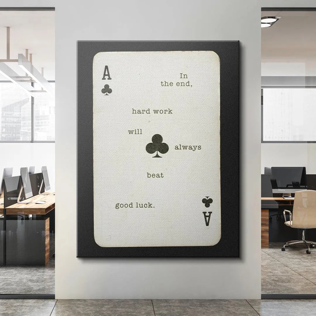 The 'Hard Work Beats Good Luck' Ace of Clubs print displayed next to a stack of inspirational business books.
