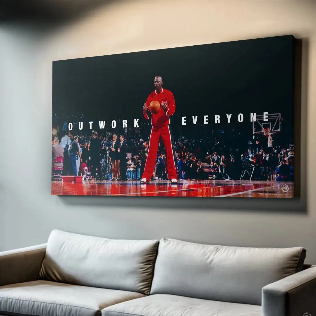 Lifestyle shot of the framed Michael Jordan - Outwork Everyone print hanging in a modern fitness room.