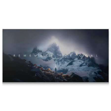 Panoramic view of a hiker facing dramatic, cloudy mountains under the caption: Remember The Goal.