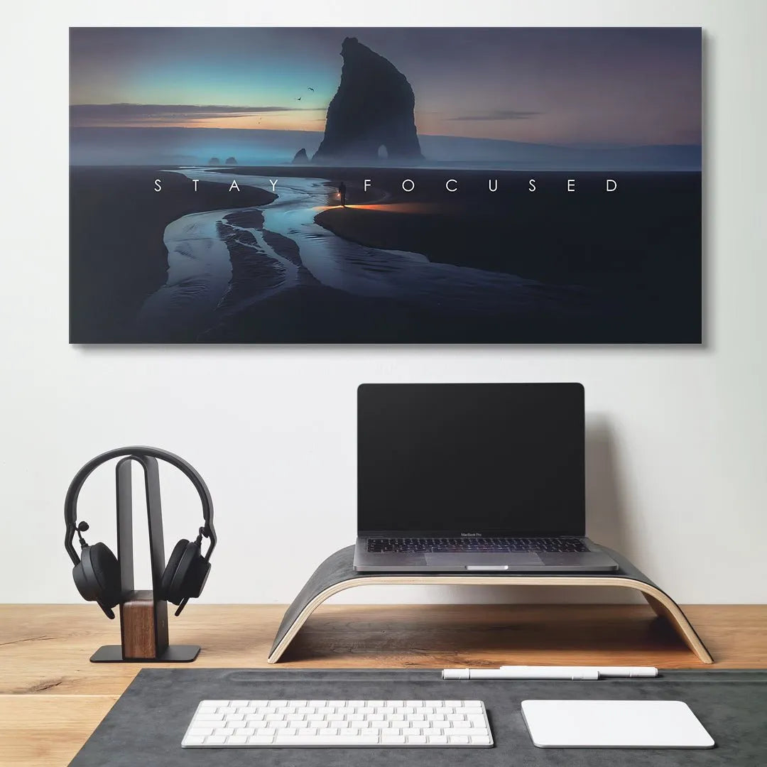 Interior lifestyle mockup showing the large "Stay Focused" print hanging above a minimalist office desk setup.